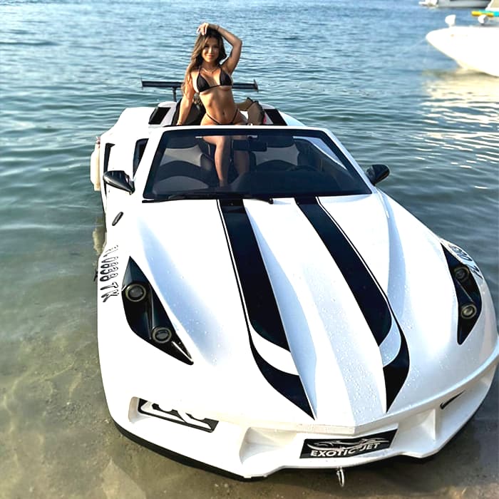 Woman in a black bikini posing on a white jet car in calm ocean water.