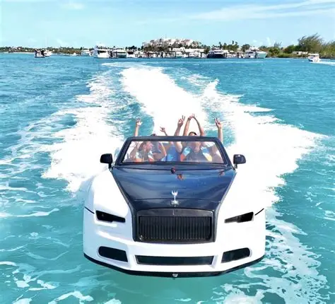 White car-shaped speedboat speeding through turquoise water with cheering passengers and a large wake.